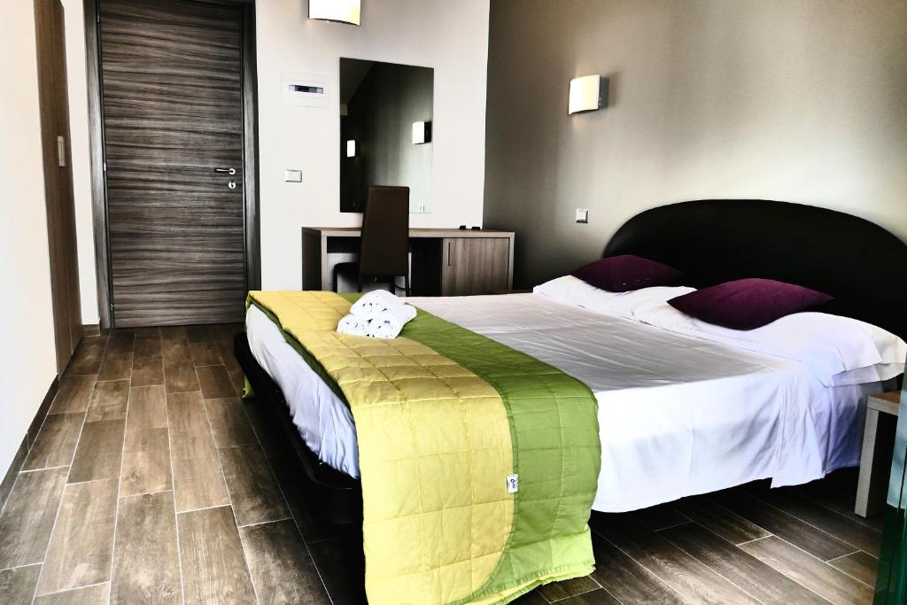 Hotel Désirée في سان بنيديتّو ديل ترونتو: غرفة نوم بسرير كبير مع شراشف بيضاء ومخدات ارجوانية