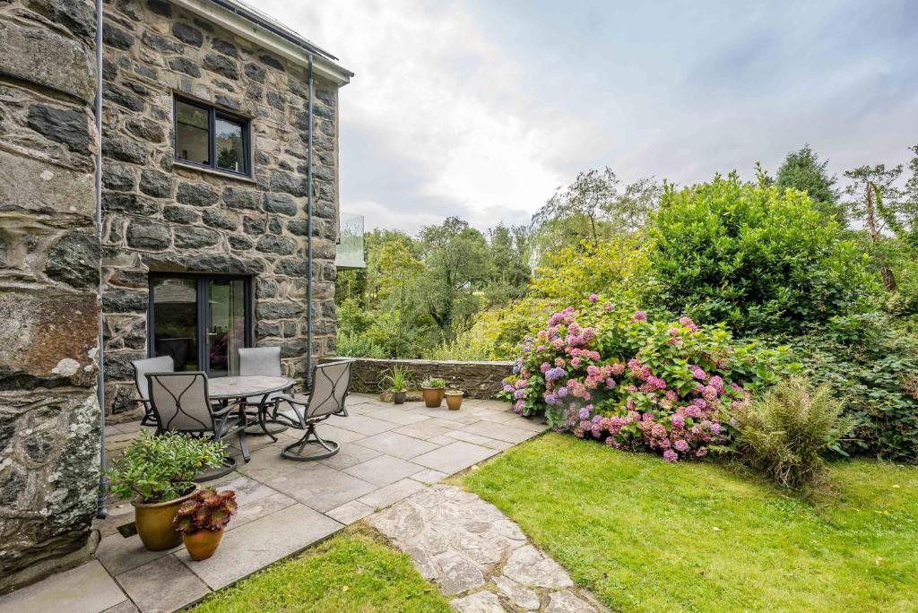 a stone house with a patio with a table and chairs at Melin-Dwyfor in Criccieth