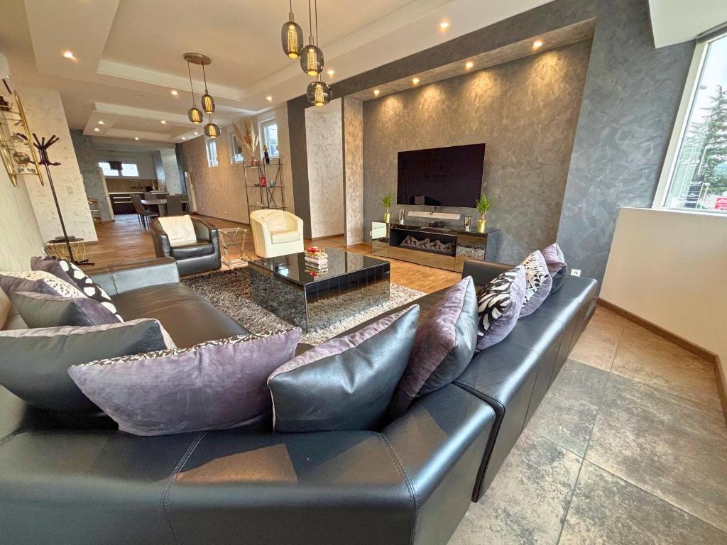 Una sala de estar con un sofá y un televisor. en GT Loft - Haut de Gamme - Parking Gratuit - Moderne & Spacieux - Commerces à Proximité, en Bischheim