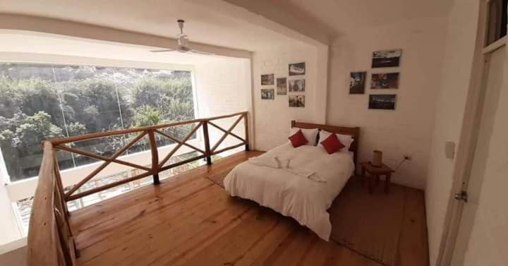 una camera da letto con un letto e una grande finestra di San Jerónimo River Lodge a Lunahuaná
