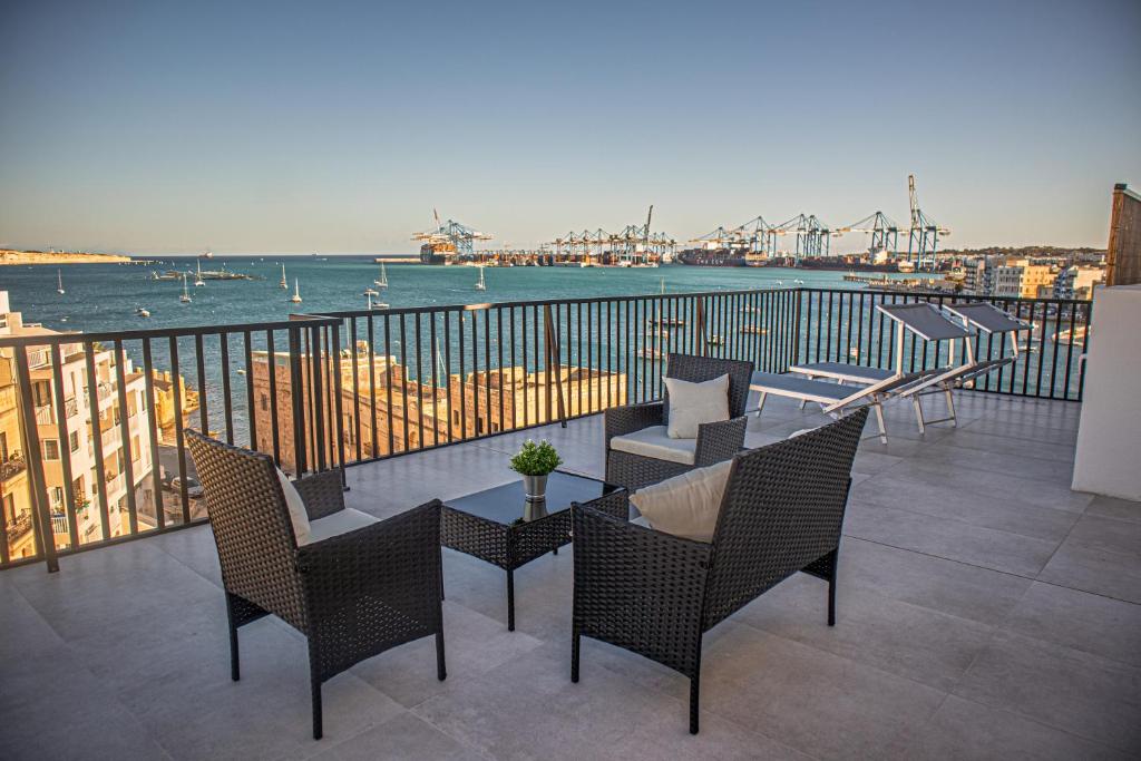 Un balcón con mesa y sillas y vista al agua. en Birzebbuga Sunset, en Birżebbuġa
