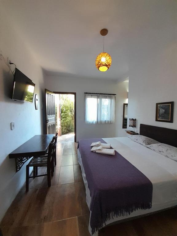 Santa Monica Hospedaria في برايا دو روزا: غرفة نوم بها سرير وطاولة ومكتب