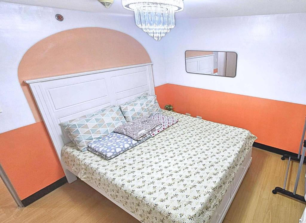 a bedroom with a bed with an orange and white headboard at Bright & Airy Loft Cambridge Village Charm in Cainta
