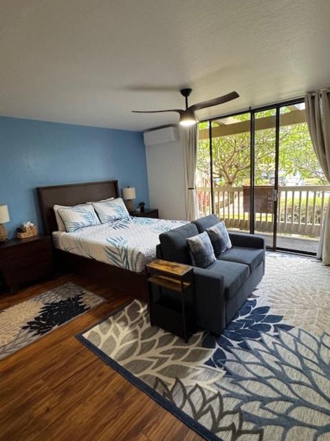a bedroom with a bed and a couch and a fan at Stylish Studio Condo Near Magic Sands Beach in Kailua-Kona