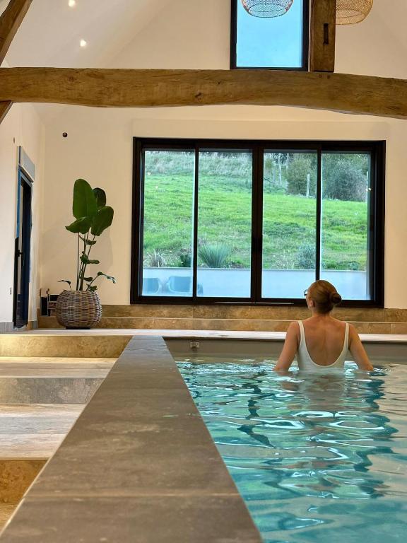 a woman sitting in a swimming pool in a house at Domaine de la Vacquerie in Alette