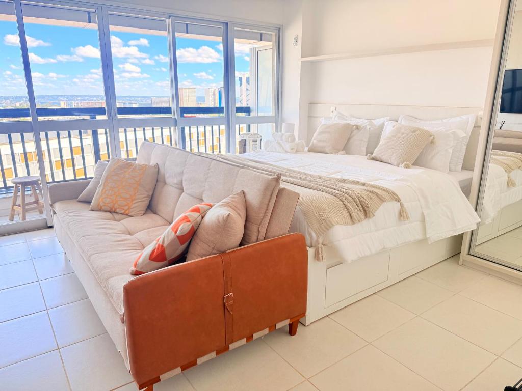 een groot bed met een bank in een kamer met ramen bij Vista Panorâmica - Hotel Vision in Brasilia