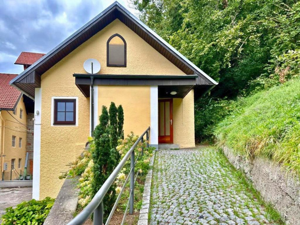 una pequeña casa amarilla con una puerta roja en Ferienhaus am Fluss, en Pinsdorf