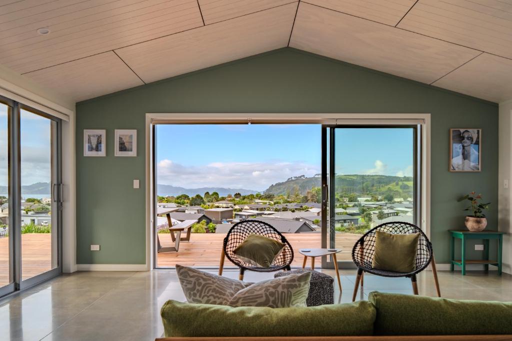 a living room with a couch and chairs at Purangi Views in Cooks Beach