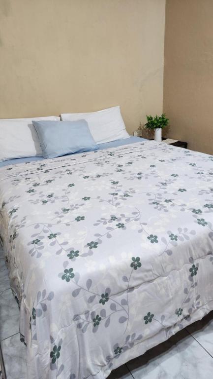 ein Bett mit einer weißen Decke mit Blumen darauf in der Unterkunft Habitación en Residencia Familiar in Asunción