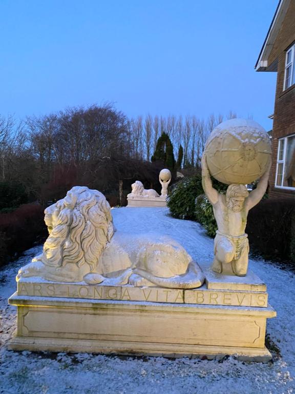 Una estatua de un león sosteniendo un globo terráqueo en un patio. en Winterwood, en Listowel