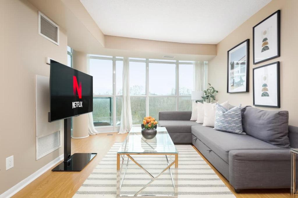 un soggiorno con divano grigio e TV di Bright & Spacious 2-BR Condo Near TOs Waterfront a Toronto
