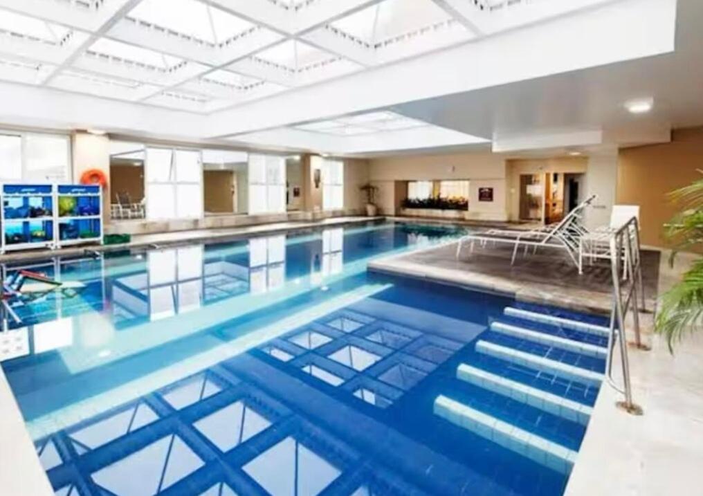 een groot zwembad met blauw water in een gebouw bij Flat no hotel Comfort em Alphaville in Barueri