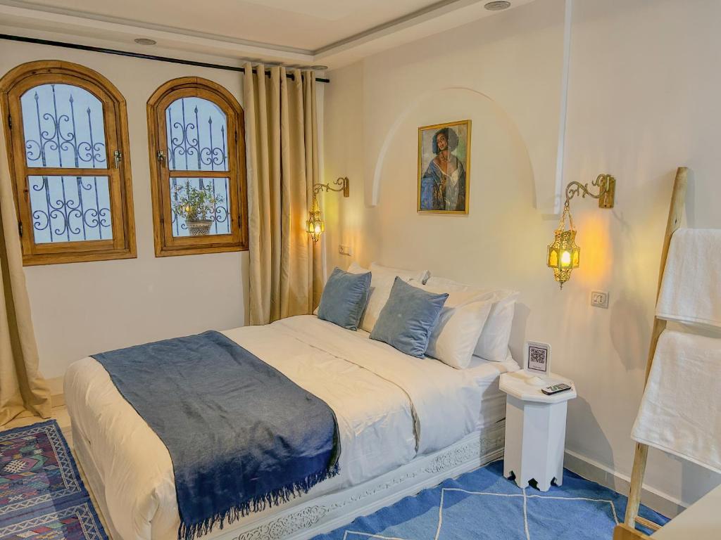 a bedroom with a bed in a room with windows at Chambre Lumineuse avec Vue Ruelle Bleue et Terrasse in Chefchaouene