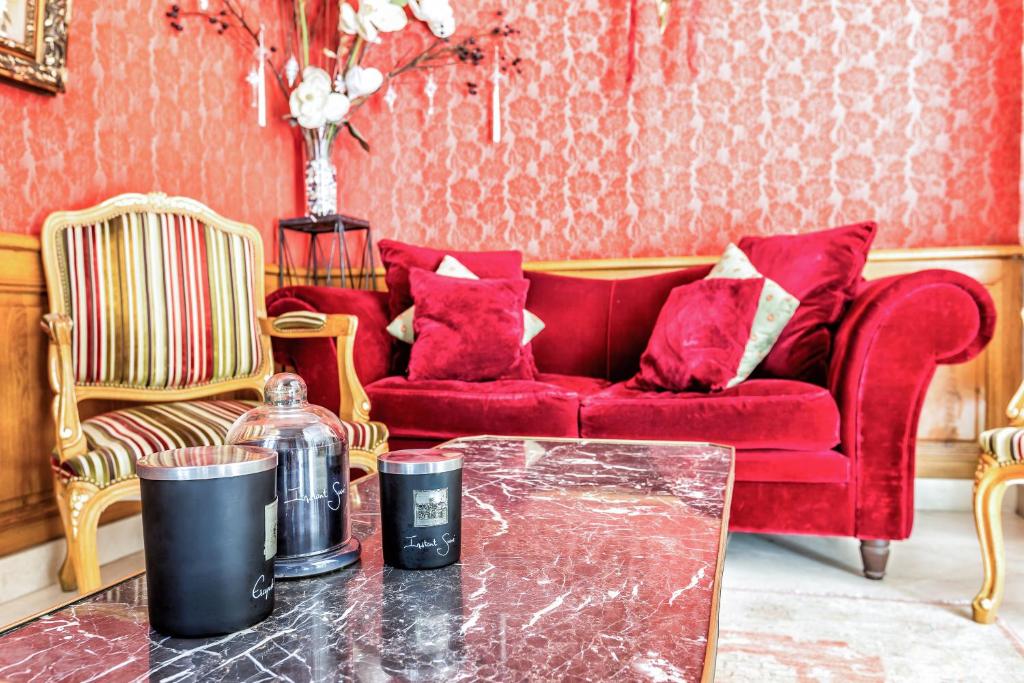 a living room with a red couch and a table at Hotel Regence Paris in Paris