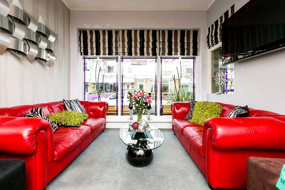 a living room with red leather couches and a glass table at Kenley Hotel in Blackpool