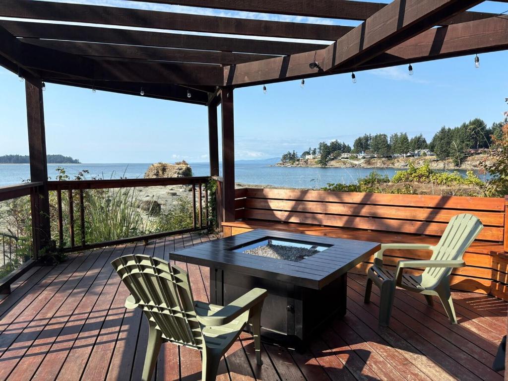 een terras met een tafel en stoelen en uitzicht op het water bij Oceanside Nature Resort in Nanoose Bay