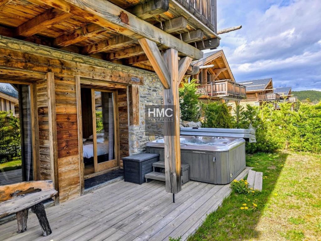 een houten terras met een hot tub en een gebouw bij Chalet K Jacuzzi et vue in Bolquere Pyrenees 2000