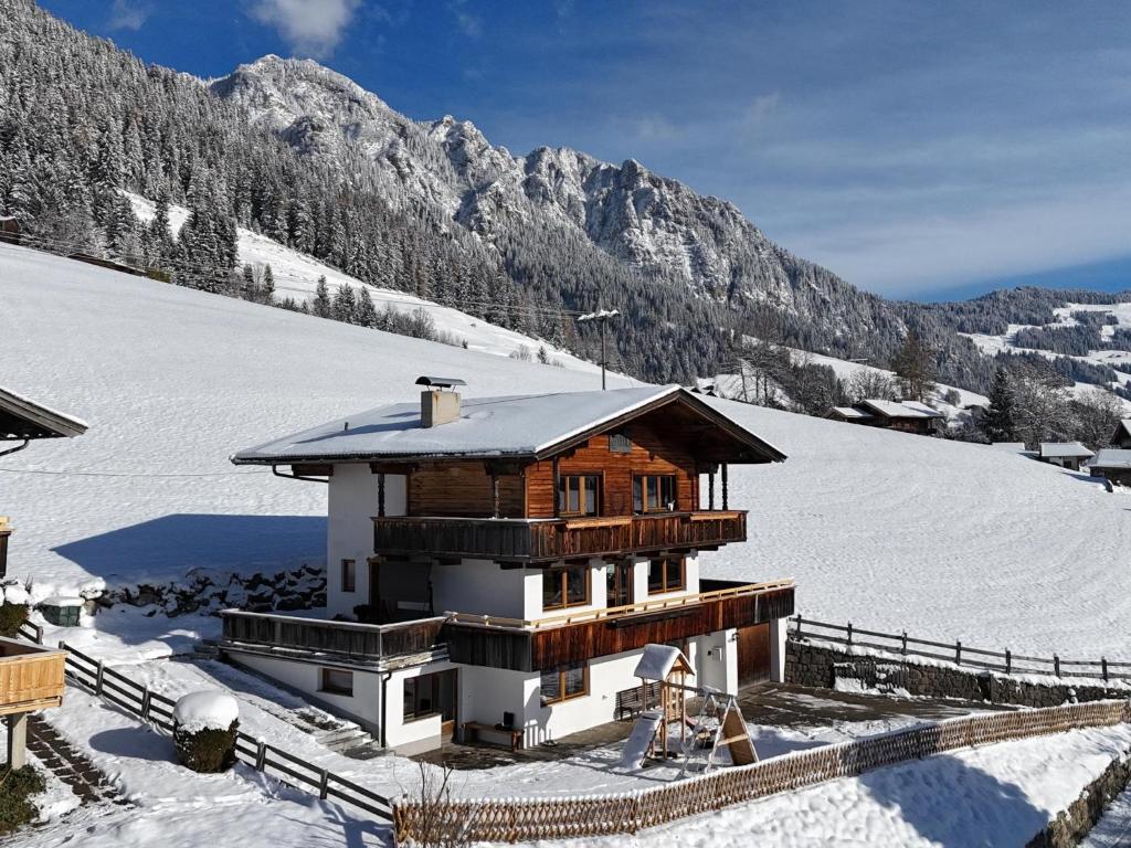 uma casa na neve com montanhas ao fundo em Tirola Chalet Alpbach em Alpbach