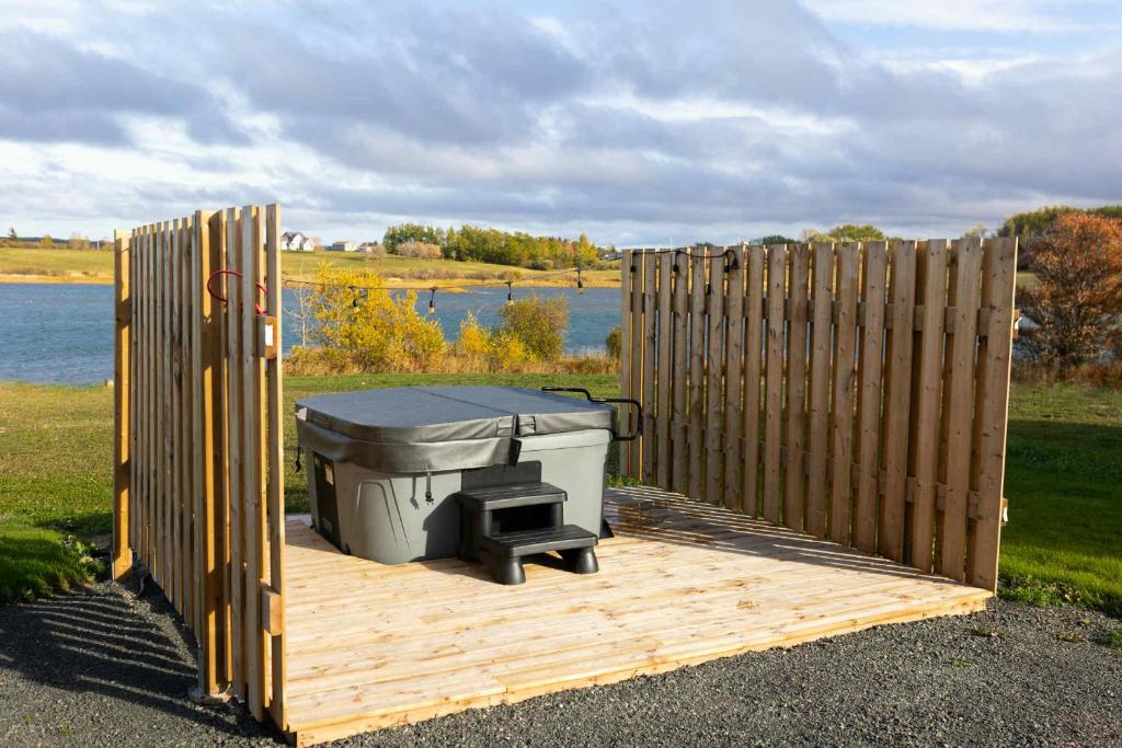 einen Grill auf einer Holzterrasse neben einem Zaun in der Unterkunft Down East Cabins in Tracadie