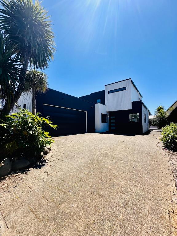 um edifício preto e branco com garagem em Modern Costal Escape-with Spa em Papamoa