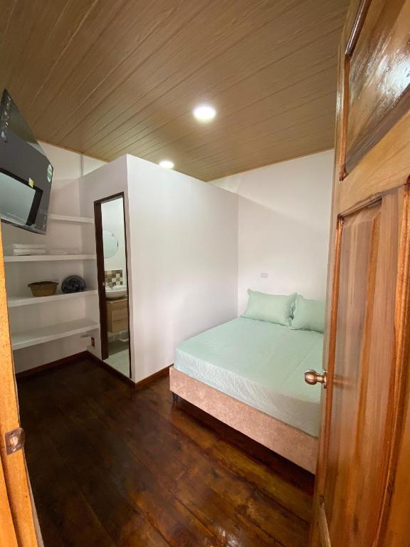 a small bedroom with a bed and a mirror at Posada Casa Linda in Pijao