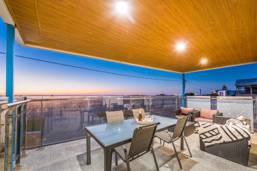 a patio with a table and chairs on a balcony at Oceans Waves - Luxury Apartment with ocean views in Lancelin