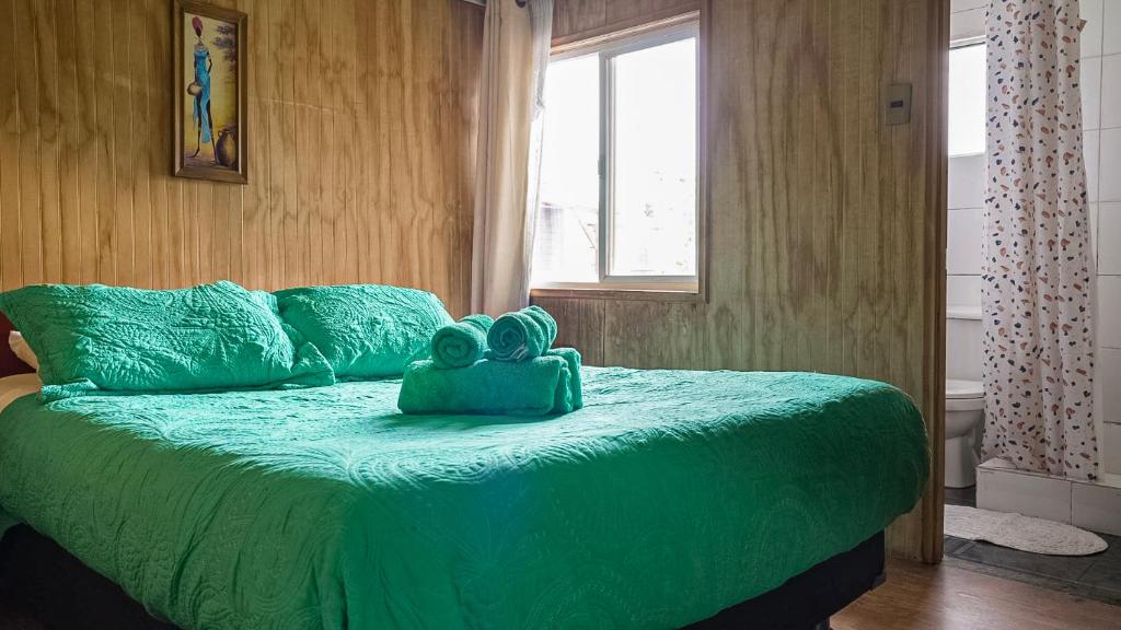 un letto verde con una borsa blu sopra di Alma Patagona Coyhaique a Coihaique