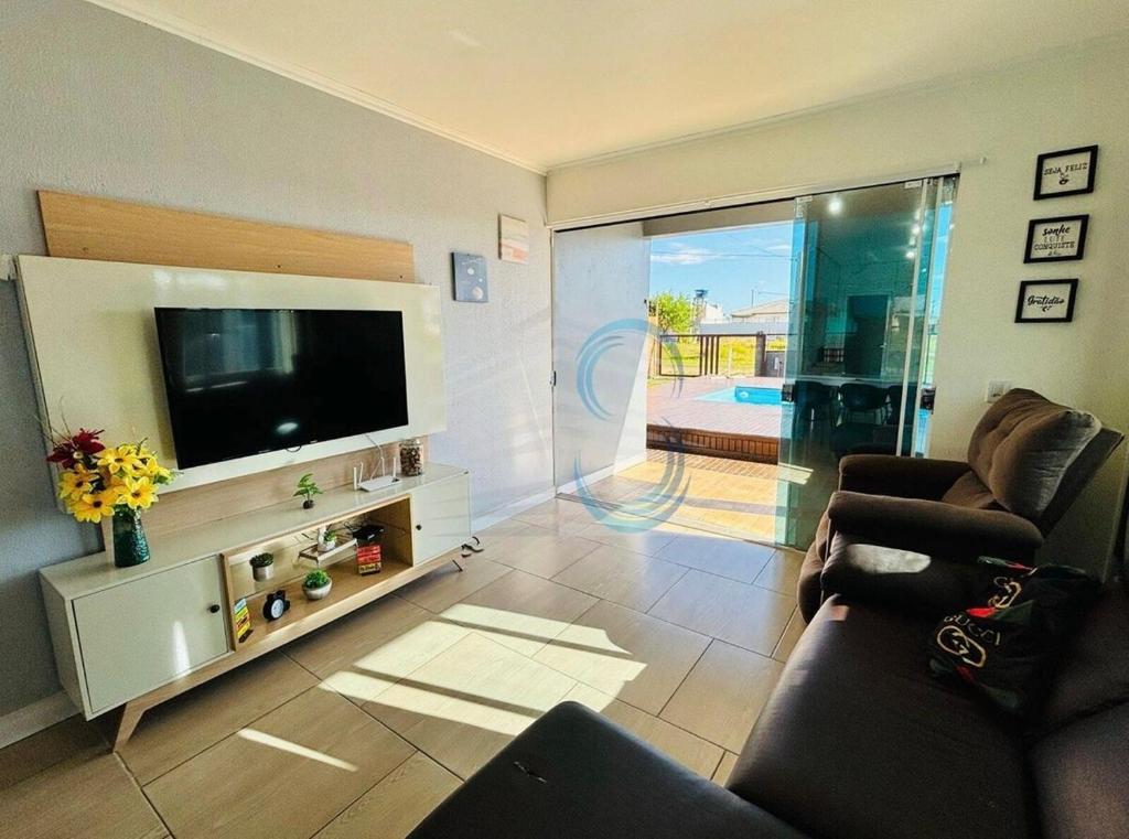 a living room with a flat screen tv and a couch at Casa com Piscina in Arroio do Sal