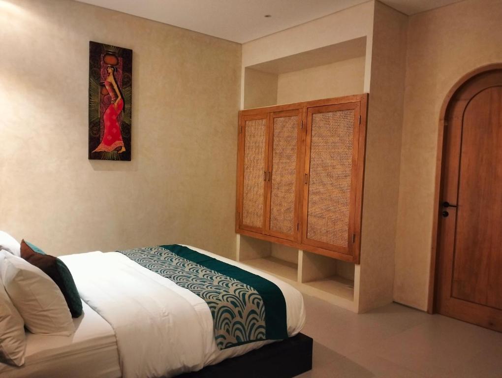 a bedroom with a bed and a wooden cabinet at Villa Puri Mesari Amed in Amed