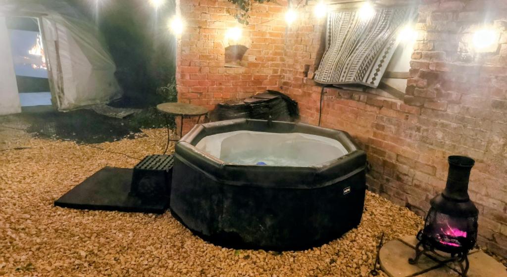 d'une baignoire installée à côté d'un mur en briques. dans l'établissement Secret Heated Dome, Hot Tub,Firepit Projector in Lincoln, à Lincoln