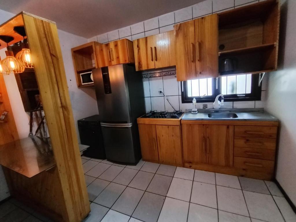 a kitchen with wooden cabinets and a black refrigerator at POUSADA TEMPORADA BIBi casa inteira com café in São Gabriel