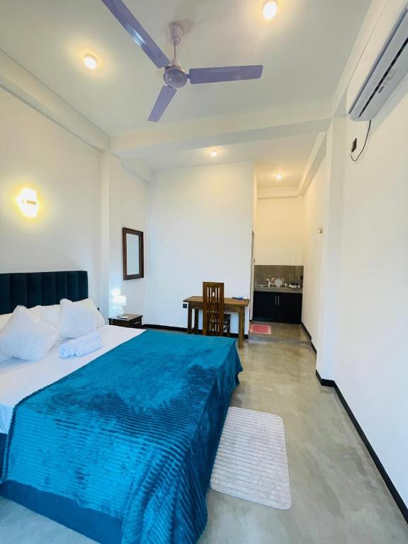 a bedroom with a blue bed and a table at Tropictide Weligama in Weligama