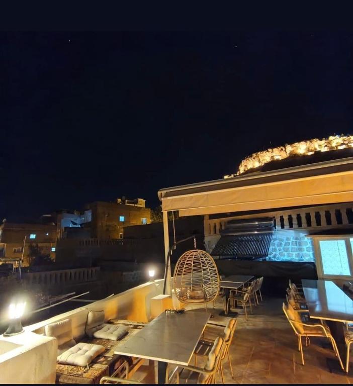 a rooftop deck with a table and chairs at night at Kasr-ı Han Konağı Otel in Mardin