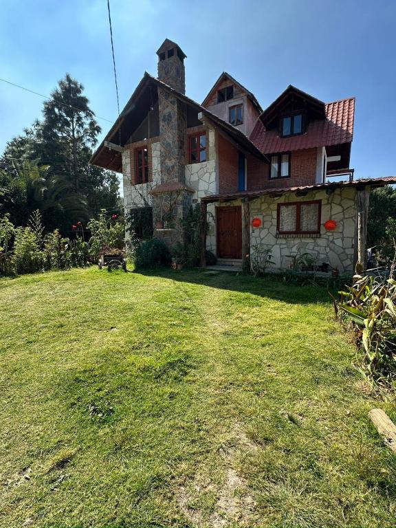a house with a grass yard in front of it at Cabaña Milagros in Huasca de Ocampo