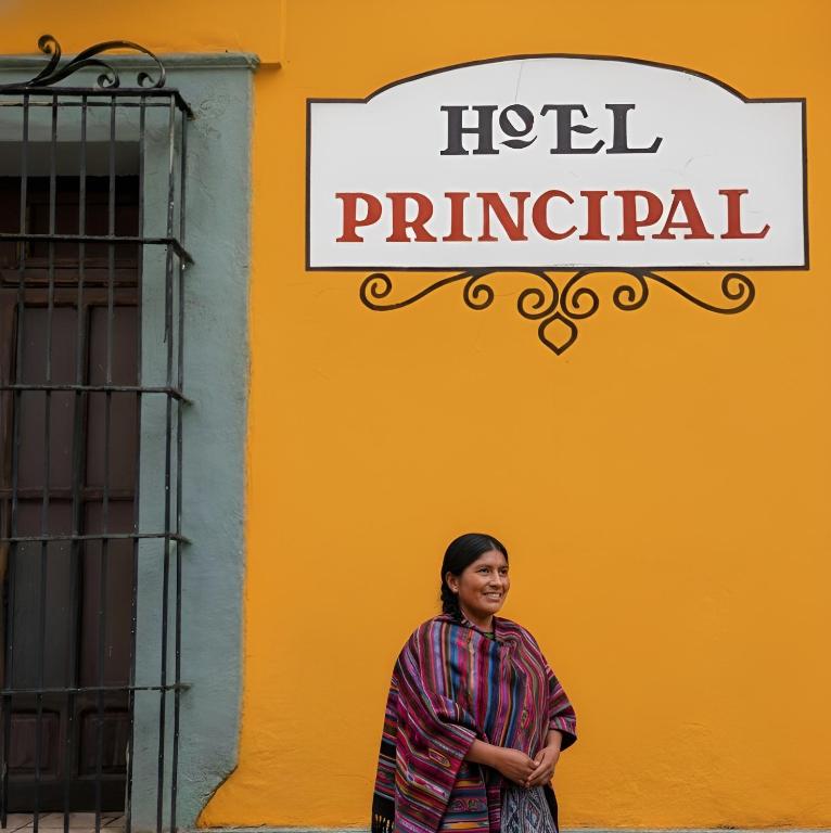 a woman standing in front of a yellow building at Hotel Principal in Oaxaca City