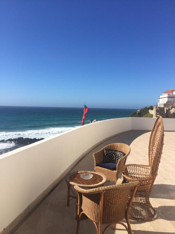 een balkon met stoelen en een tafel en de oceaan bij Residencial Real Guest House in Sintra