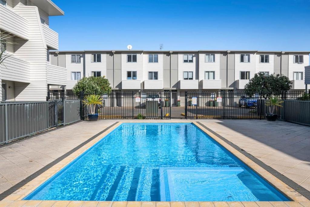 una piscina frente a un edificio de apartamentos en Right Opposite the Beach!, en Orewa