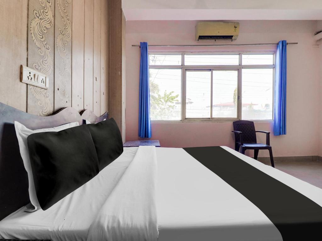 um quarto com uma cama grande com cortinas azuis e uma janela em Hotel O Gp Homestay em Dehradun
