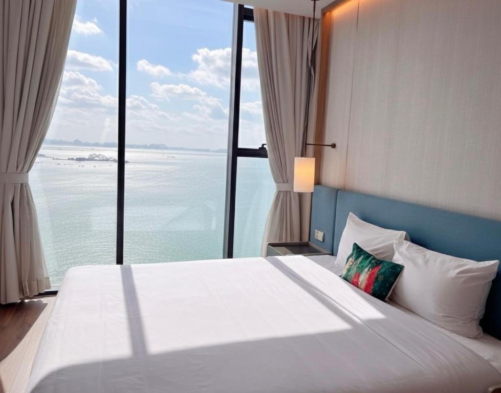 a bedroom with a large bed with a view of the ocean at A La Carte Ha Long Oceanview Fireworksview Panoramic 2BR2WC suite with balcony in Ha Long