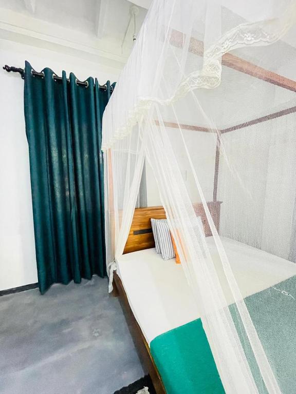 a bedroom with a bed with a mosquito net at Double G Motel in Weligama