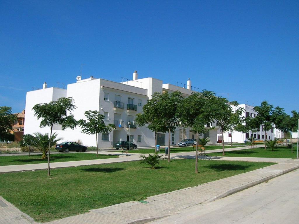 un edificio blanco con árboles delante de él en Apartamentos Conil Alquila, en Conil de la Frontera