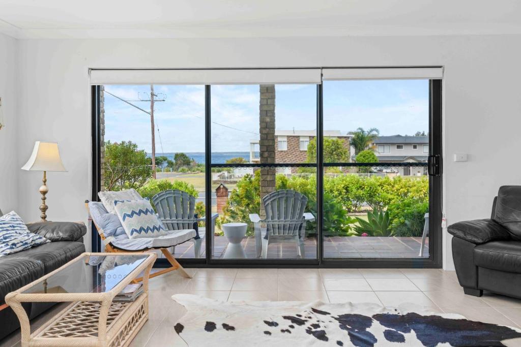 a living room with a couch and a glass door at Summer-Salt by Experience Jervis Bay in Vincentia