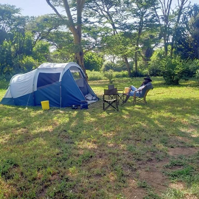 a person sitting in a chair next to a tent at Majimoto Bushpig Camp in Narok
