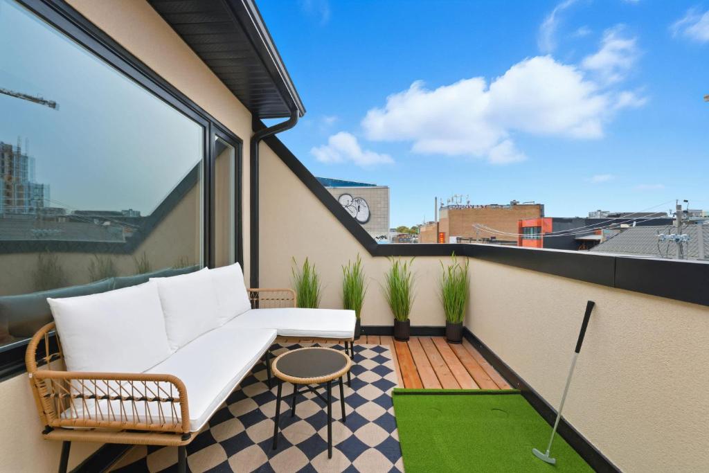 un balcon avec un canapé blanc et une table dans l'établissement Stylish 3BR CN Tower Views & Patio Mini Putt, à Toronto