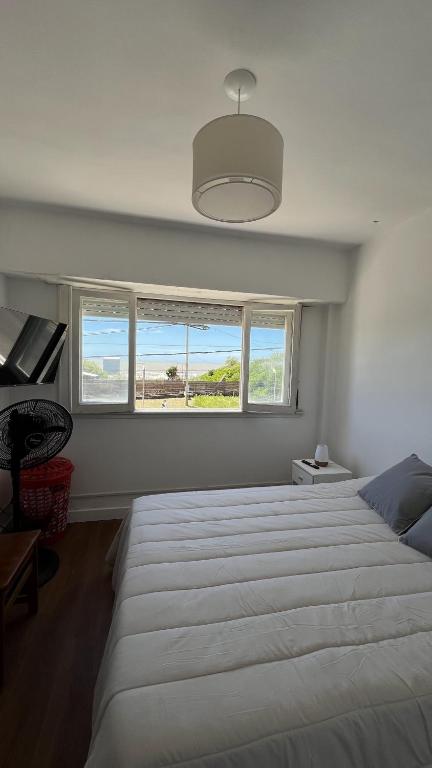 a bedroom with a large white bed and two windows at La gracie in San Bernardo