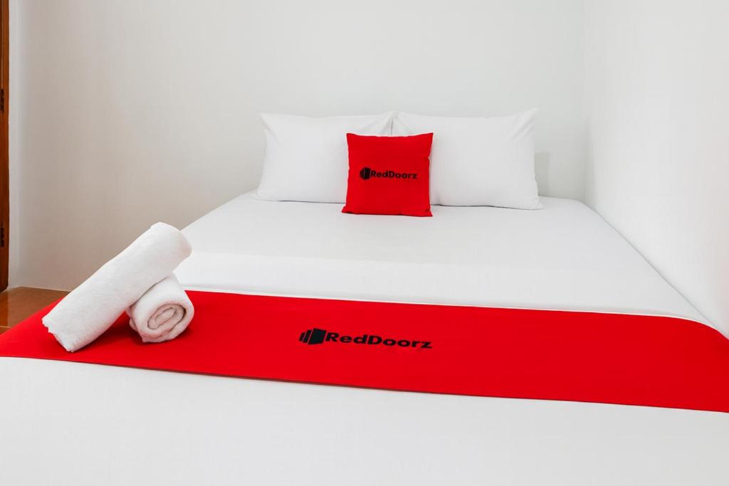 a red and white bed with a red pillow on it at RedDoorz near Pantai Ujung Genteng 2 in Ujunggenteng