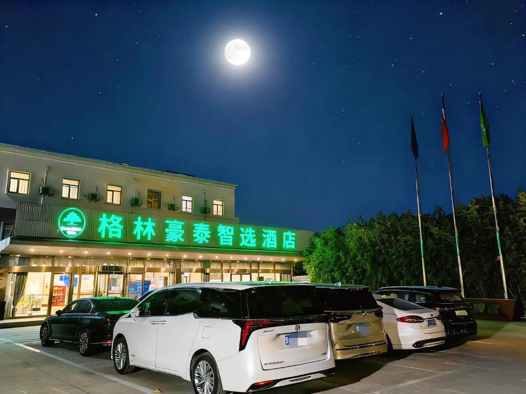 une voiture blanche garée dans un parking en face d'un bâtiment dans l'établissement Greentree Inn Express Beijing Capital International Airport&格林豪泰智选酒店北京首都国际机场店, à Pékin