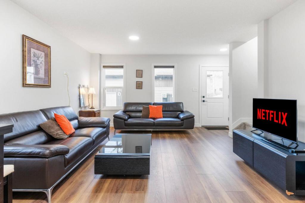 a living room with a leather couch and a television at Spacious Home • 3BR • Close to Whyte and Downtown in Edmonton