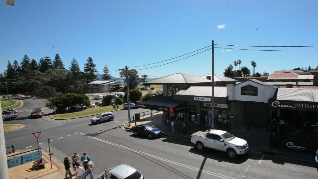 伯马吉Beach Pad Unit1, 2 Wallaga Street, Bermagui的街景，汽车停在公交车站。