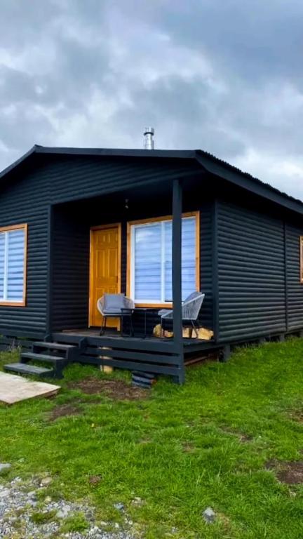 a black house with a picnic table in front of it at Cabaña Licarayén in Puerto Varas
